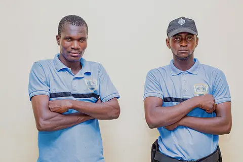 Deux agents en uniforme se tenant à un poste, bras croisés.