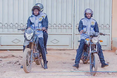 Deux agents casqués sur leurs motos devant un portail.